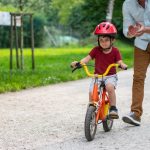 little-boy-learning-to-ride-a-bicycle-with-support-from-his-father-picture-id1213868636