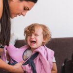 woman-trying-to-get-her-toddler-ready-for-the-kindergarten-but-the-picture-id1287223798