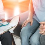 Infertility problem with marriage couple concept. A fertility doctor or reproductive endocrinologist with man and women holding hand together in therapy consult session of inability to pregnant.