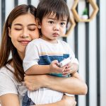 Portrait of a beautiful asian mother with her cute little son with pleasure spending time together, Young mom hugging on a back child, happy family life, enjoying family time together