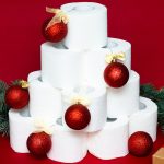 Christmas tree made from rolls of toilet paper, decorated with shiny balls, a gift and fir branches on a red background