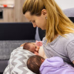 Mother holding and breastfeeding her twin babies.