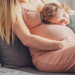 Little baby girl relaxing on mom’s pregnant belly – Pregnant mother with a toddler – Family concept